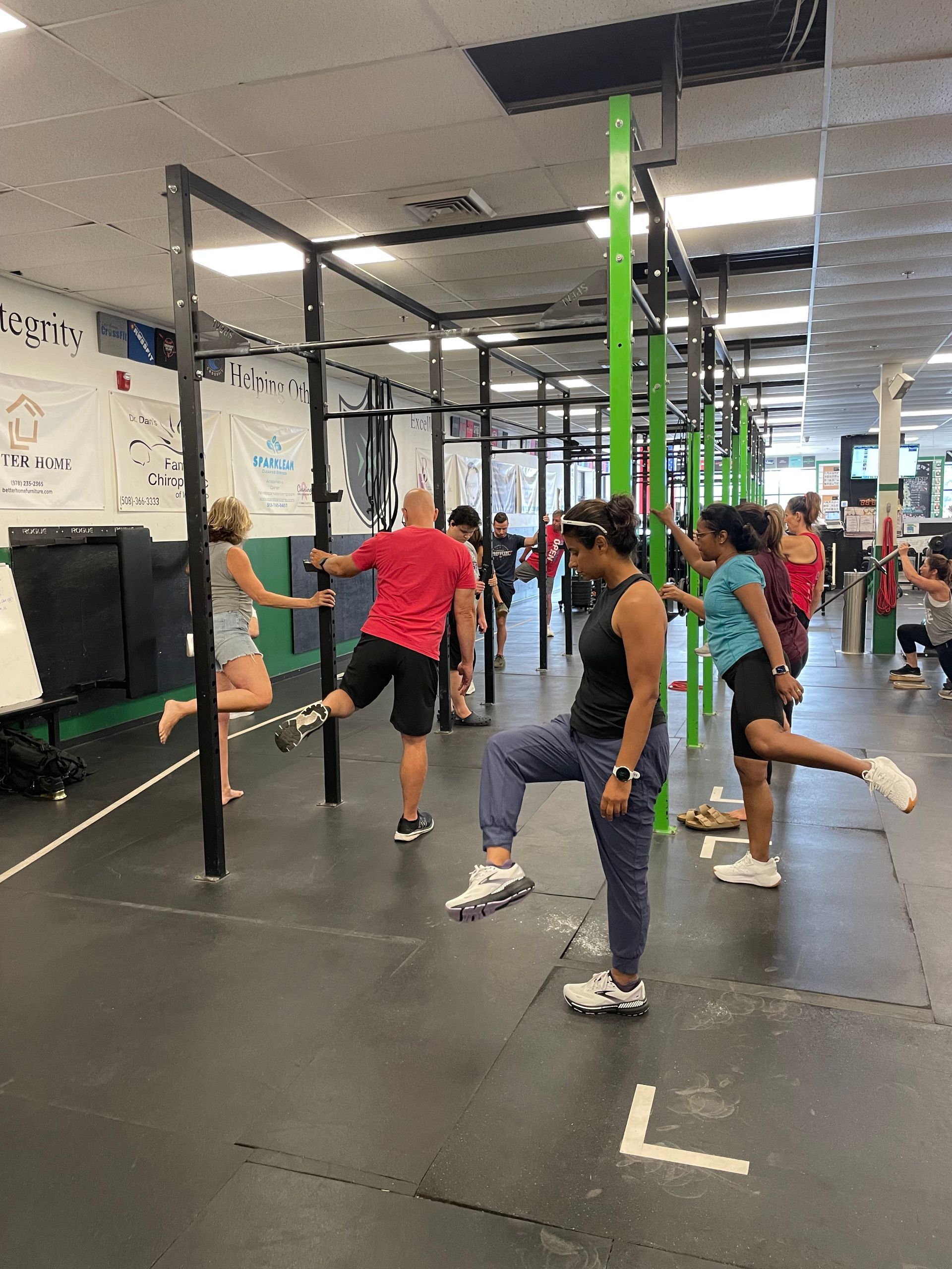 A woman in a white shirt is lifting a barbell in a gym.