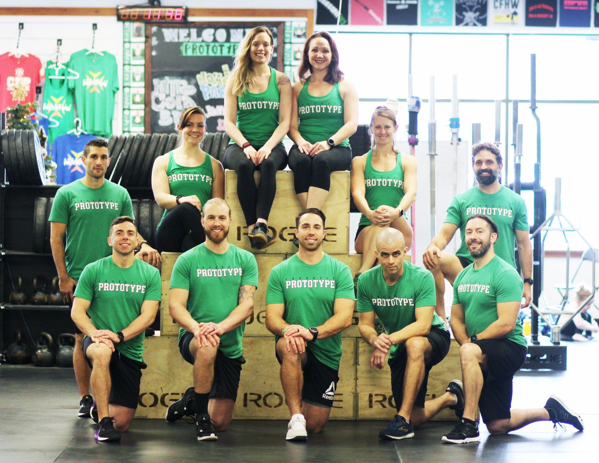 A group of people in green shirts are posing for a picture in a gym.