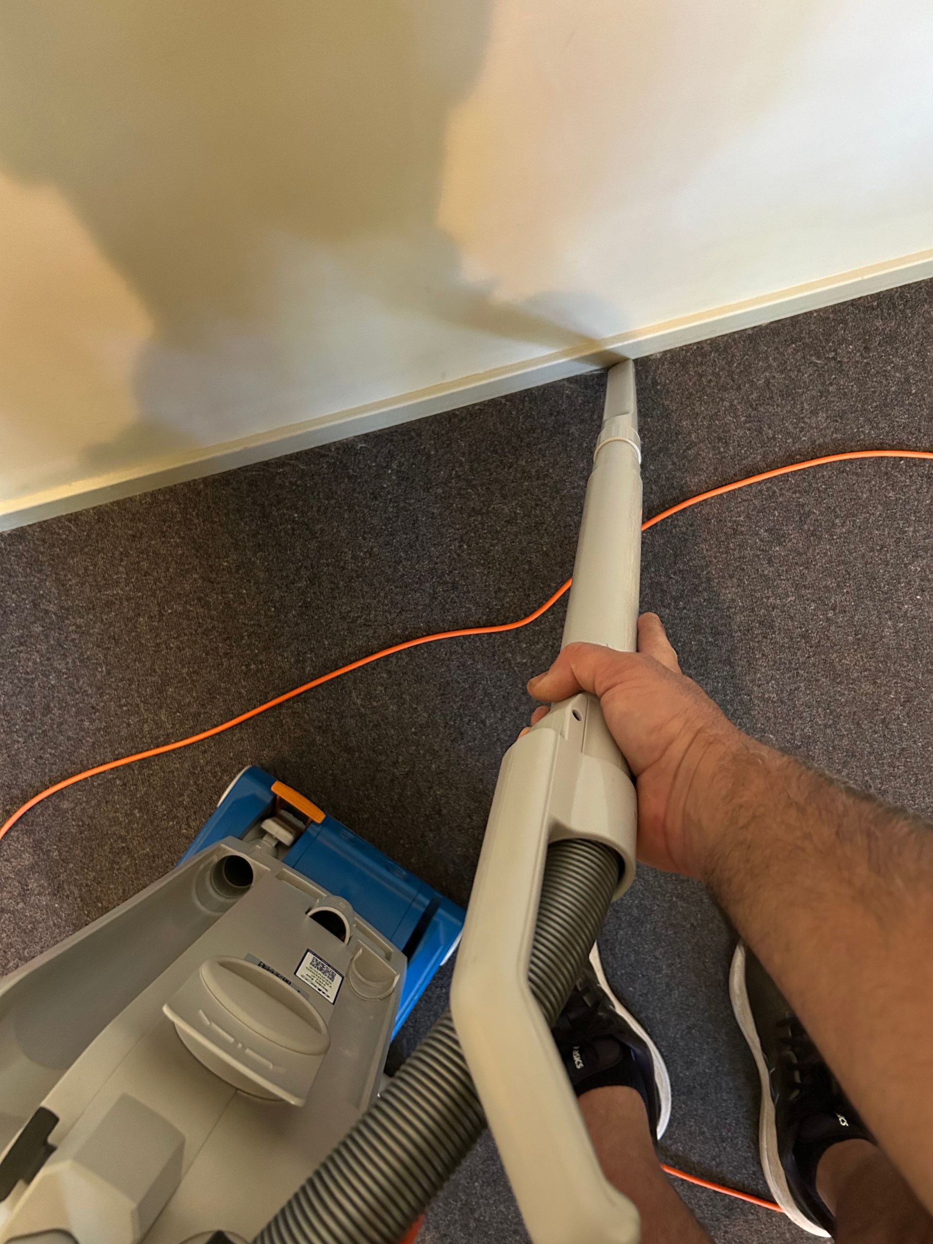 A Woman is Cleaning a Green Couch With a Vacuum Cleaner — Rugrats Carpet Cleaning Service In Diamond Beach, NSW