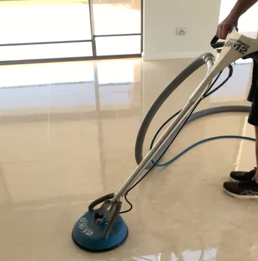 A Man is Cleaning a Tiled Floor With a Machine — Rugrats Carpet Cleaning Service In Charlotte Bay, NSW