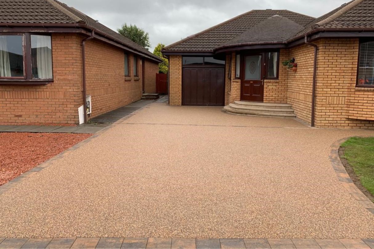 New resin driveway in a gold colour with dark brown blocks for edges.