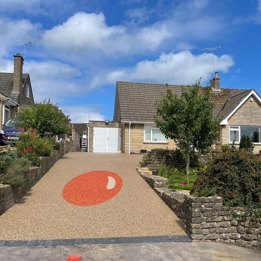 Brown resin driveway, with a big orange resin circle, leading up to a bungalow.