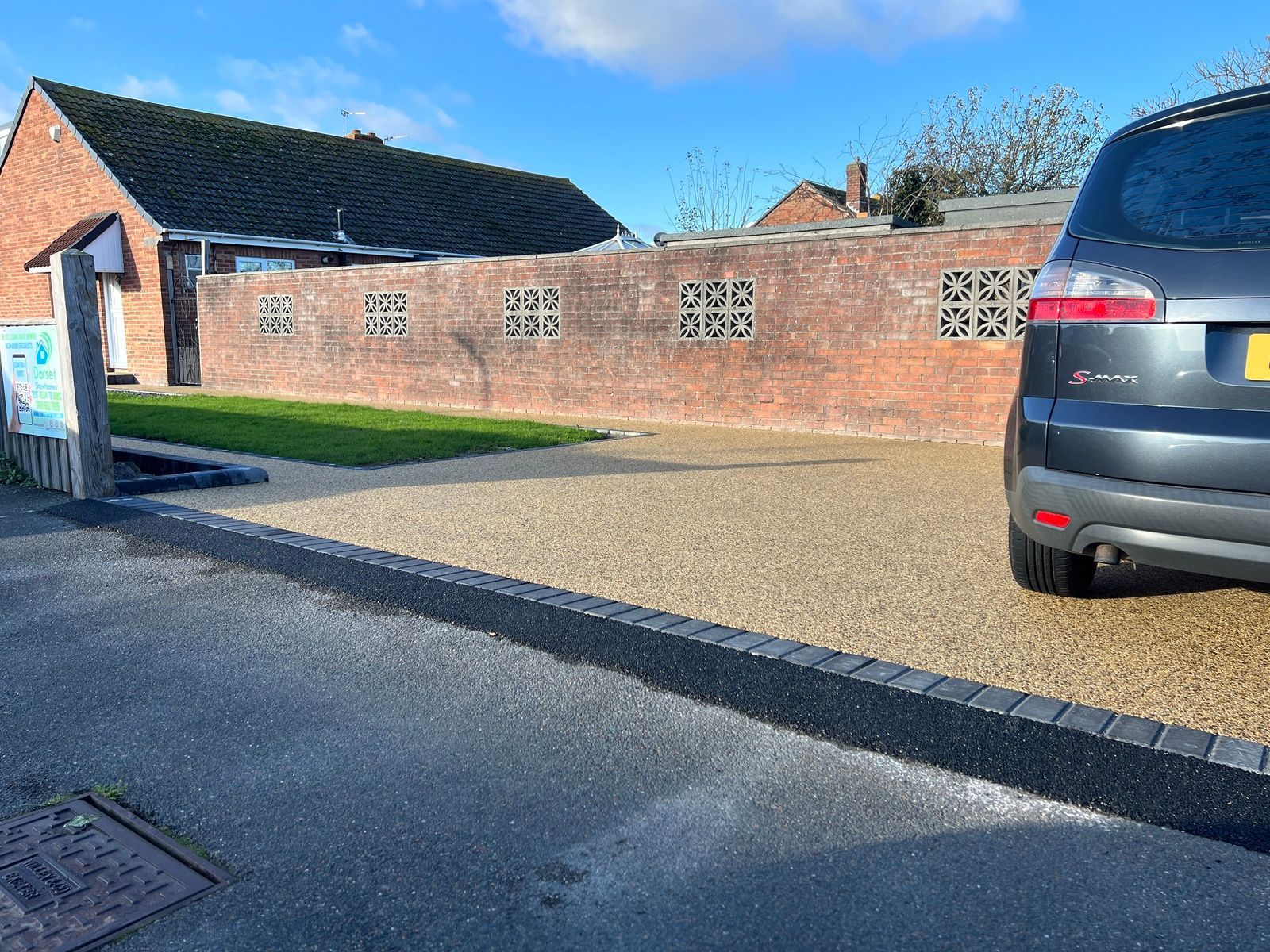 Gold colour resin driveway, with a black border, and a car.