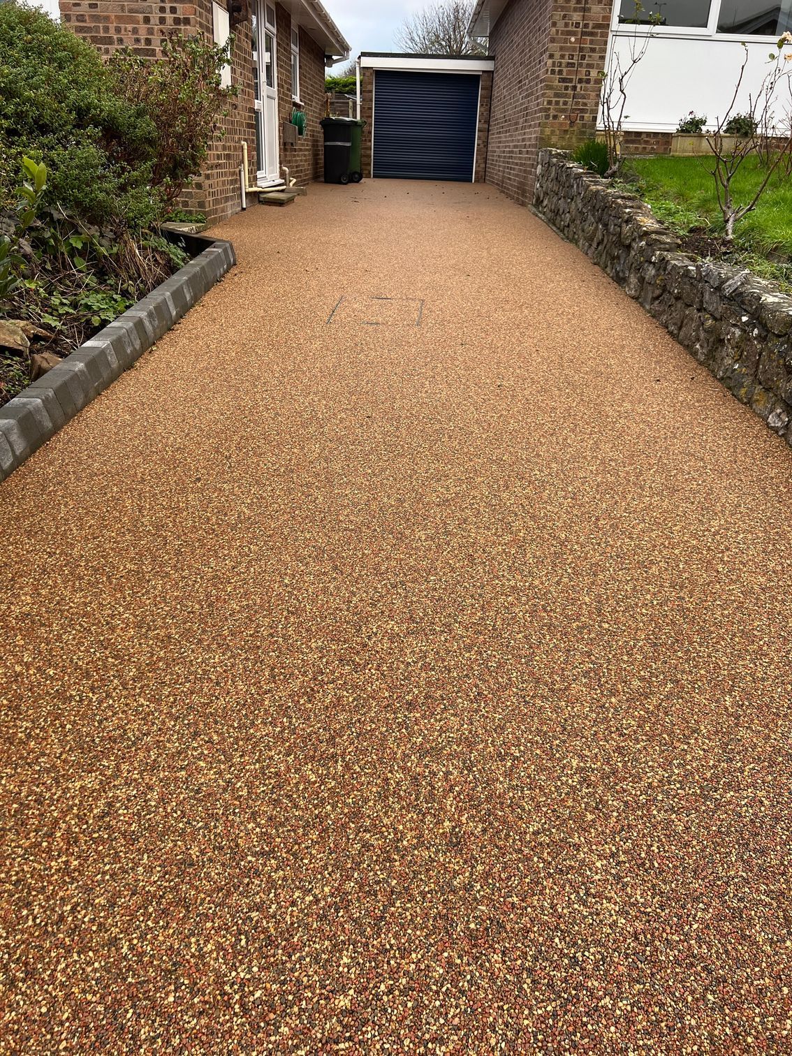 A gravel driveway leading to a house with a garage.