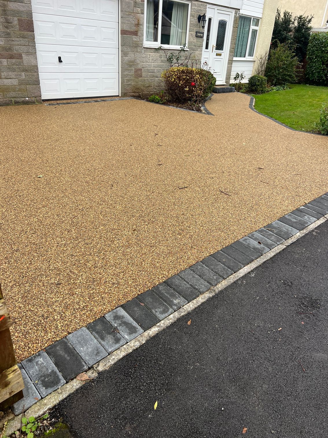 A driveway with gravel and bricks in front of a house.