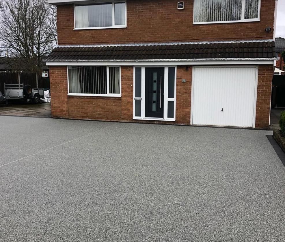 A brick house with a garage and a driveway in front of it.