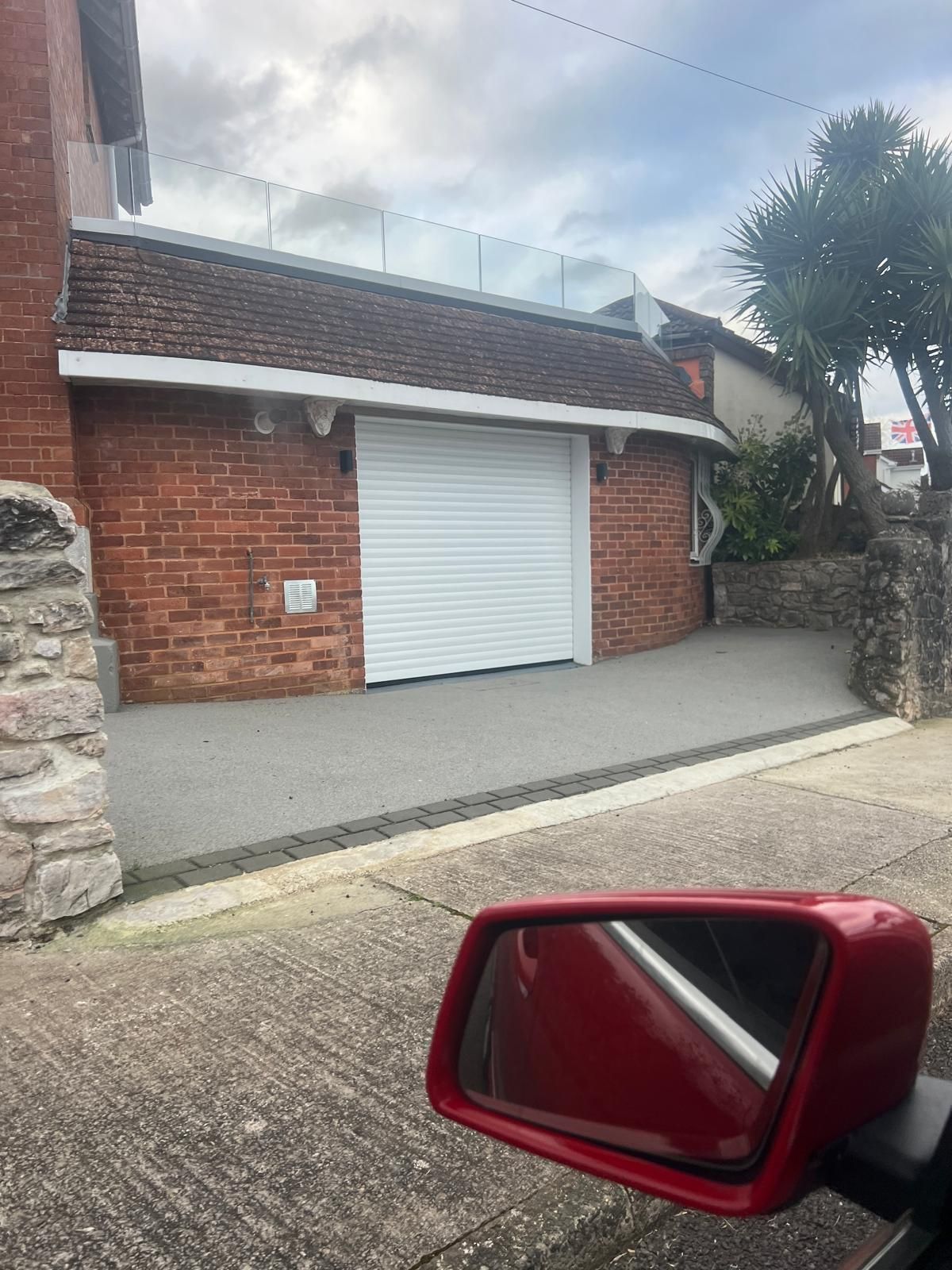 A red car is parked in front of a garage door.