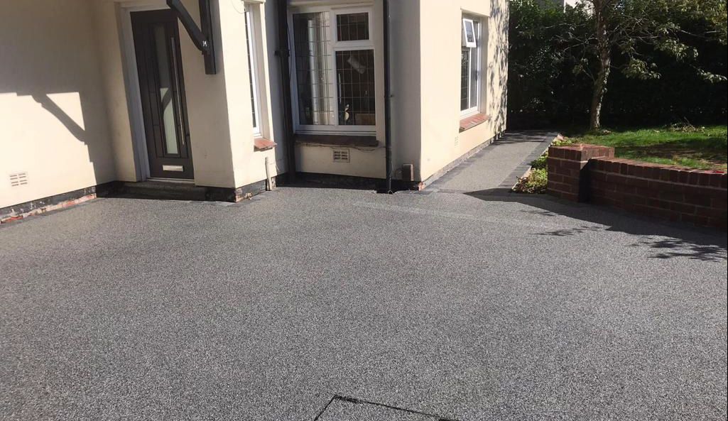 A driveway leading to a house with a concrete driveway.