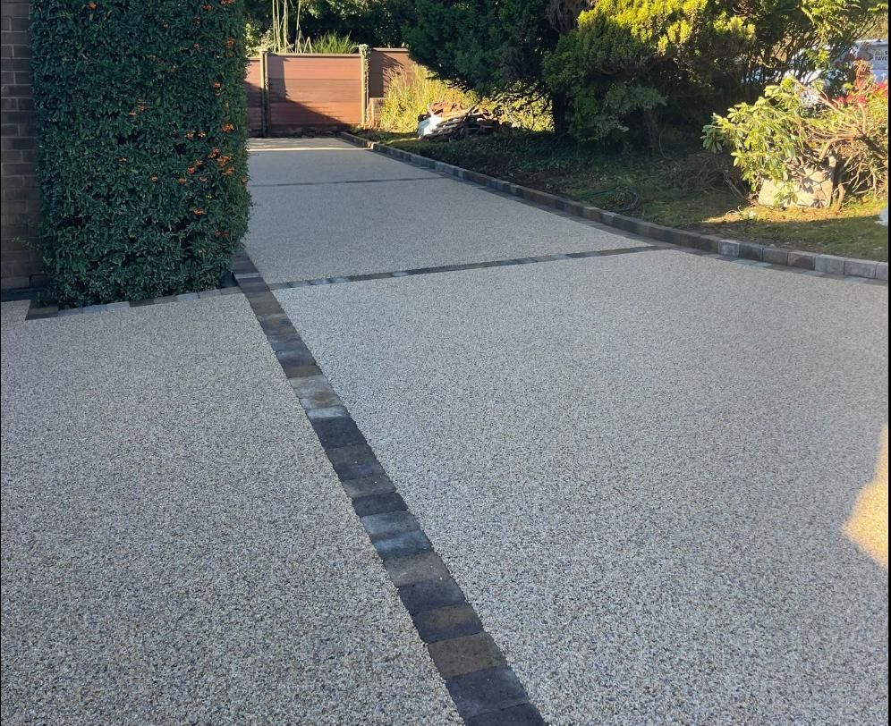 A concrete driveway with a black stripe on the side of it.