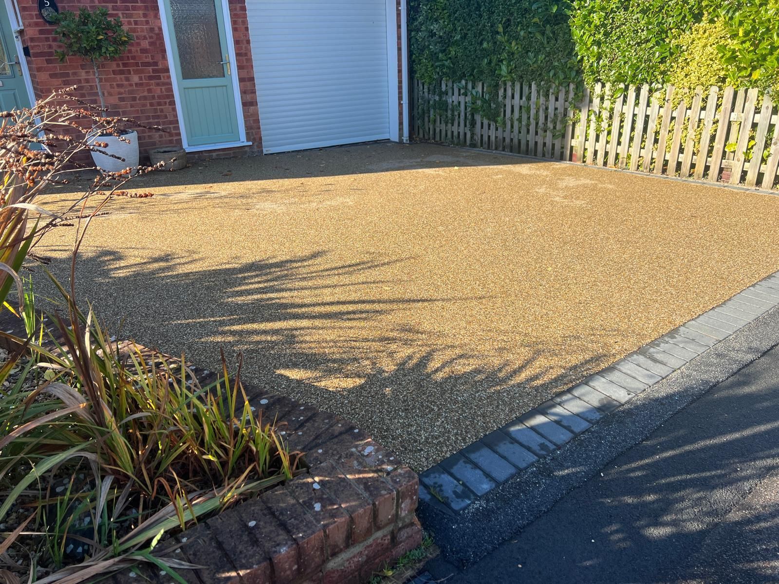 A driveway with a fence and a garage in the background.