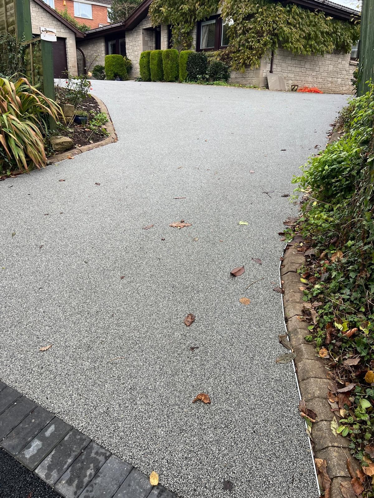 A gravel driveway leading to a house with a brick curb.