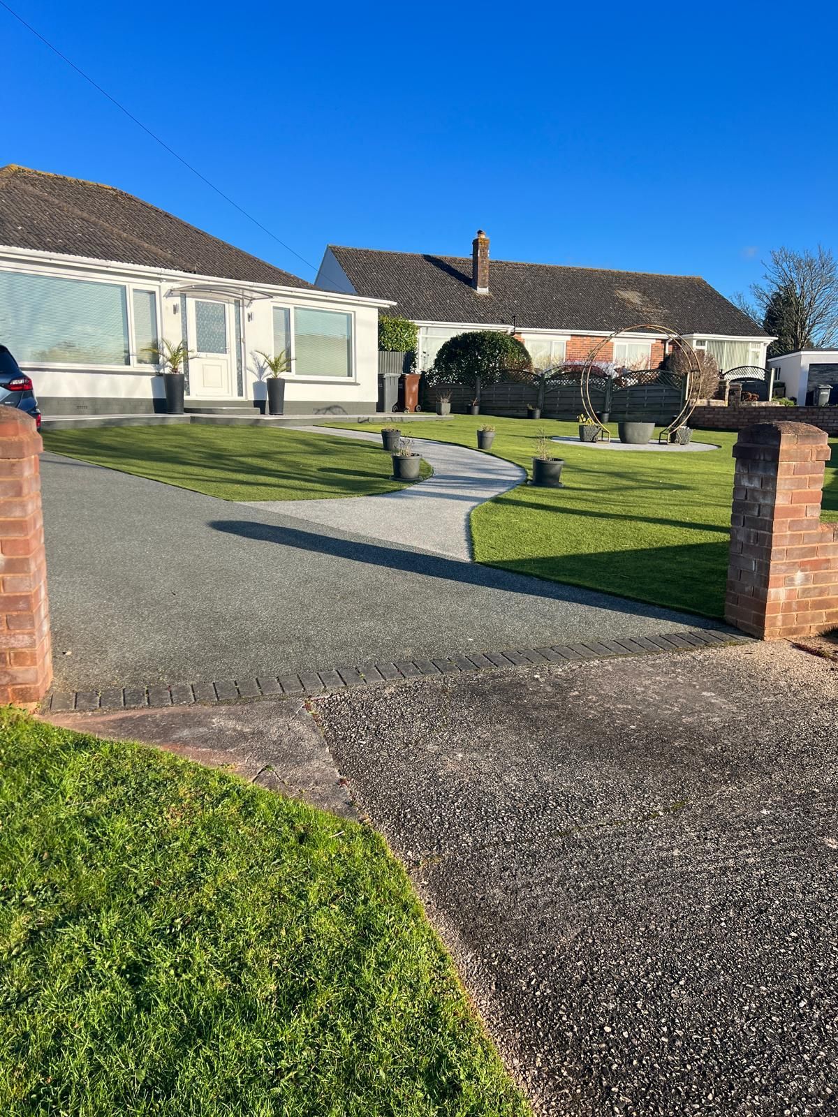 A driveway leading to a house with a blue sky in the background.