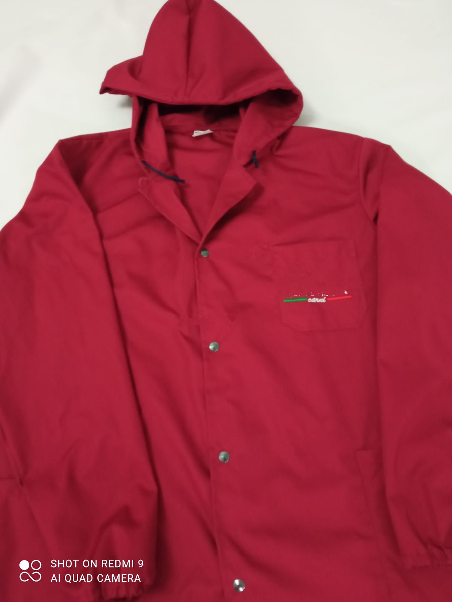 Una giacca rossa con cappuccio è su una superficie bianca