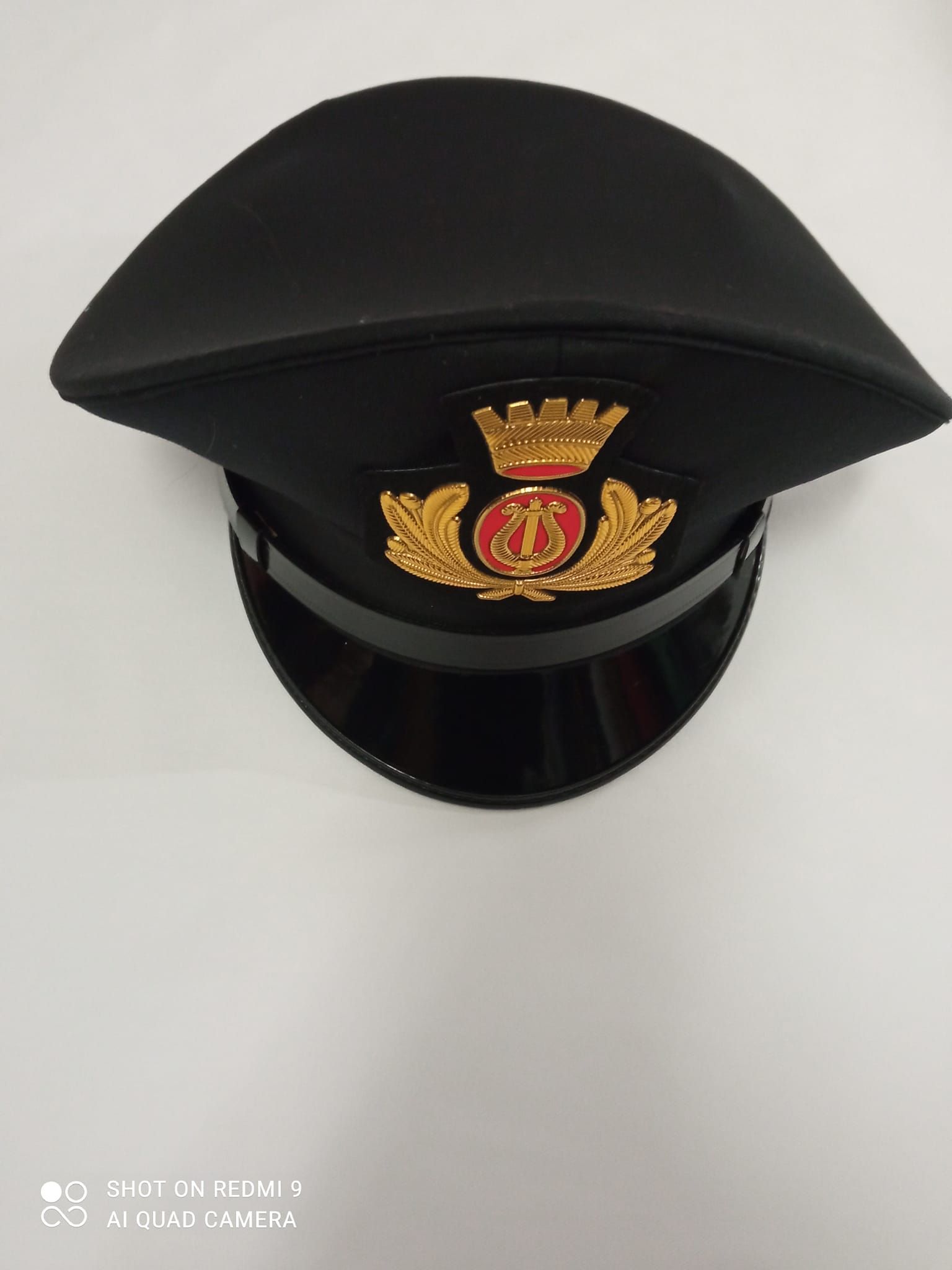 Un cappello nero con una corona d'oro è posto su una superficie bianca.