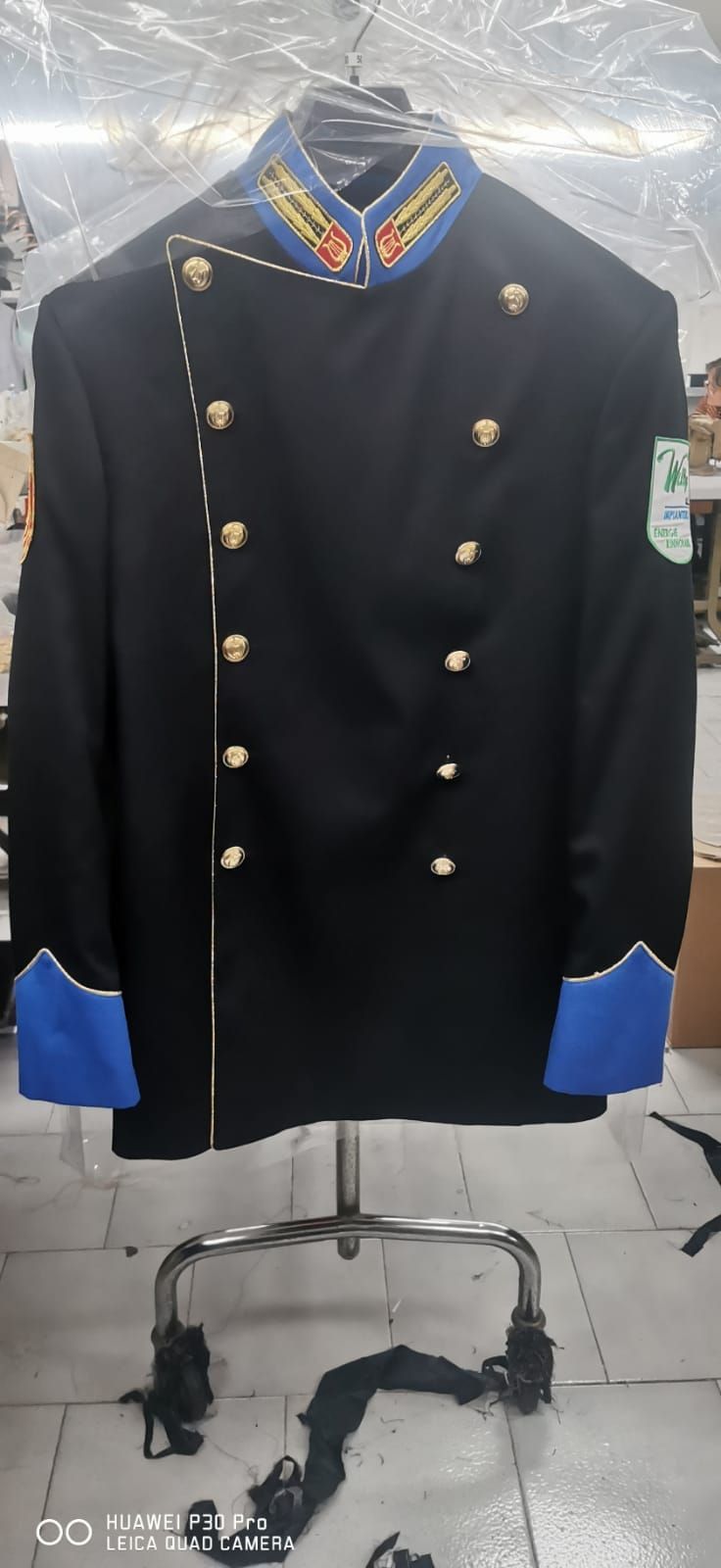 Una giacca nera con finiture blu è appesa a un attaccapanni.