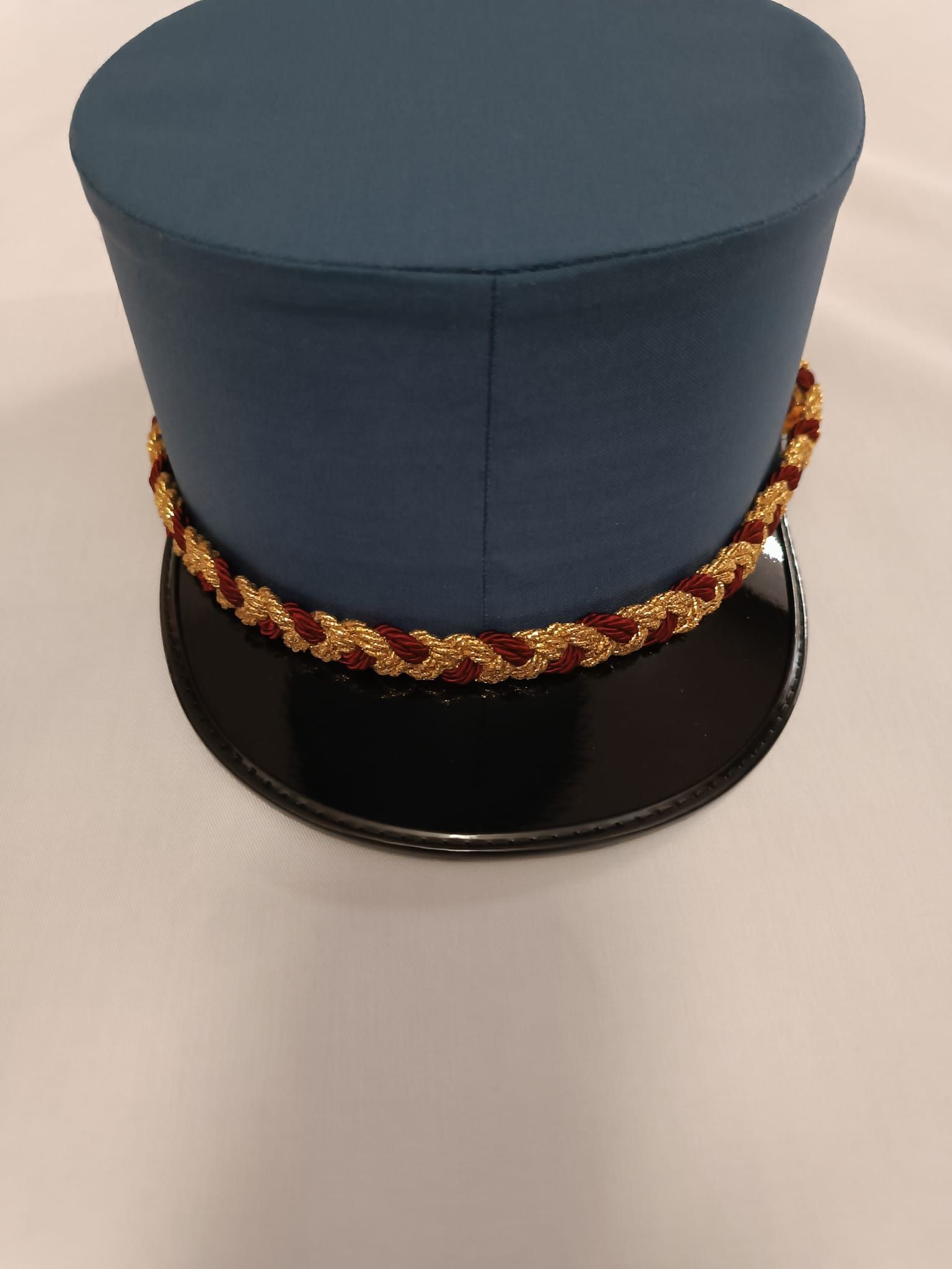 Un cappello a cilindro blu con finiture dorate è appoggiato su una superficie bianca