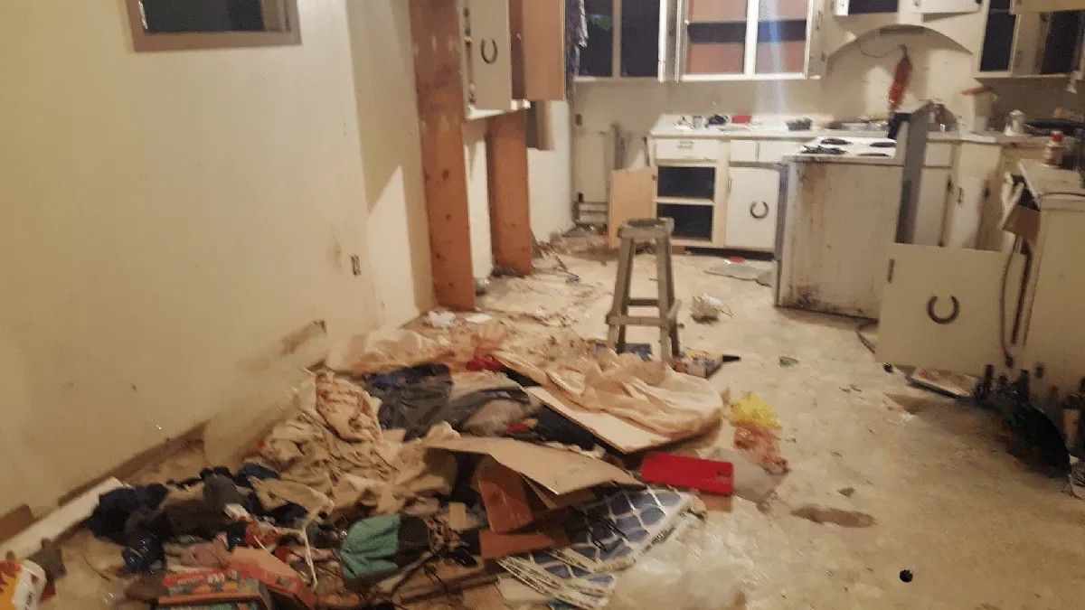 A kitchen with a lot of trash on the floor.