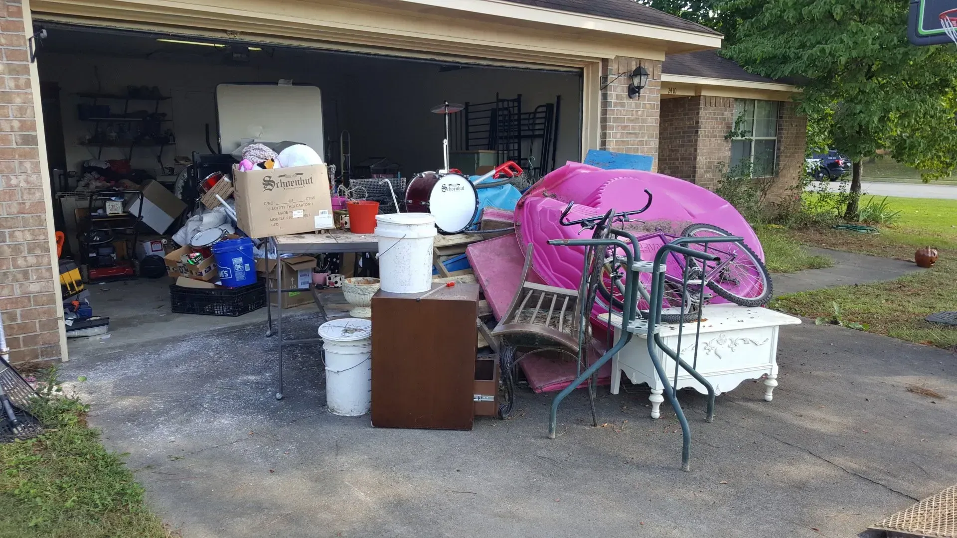 A garage filled with lots of junk and a pink umbrella.