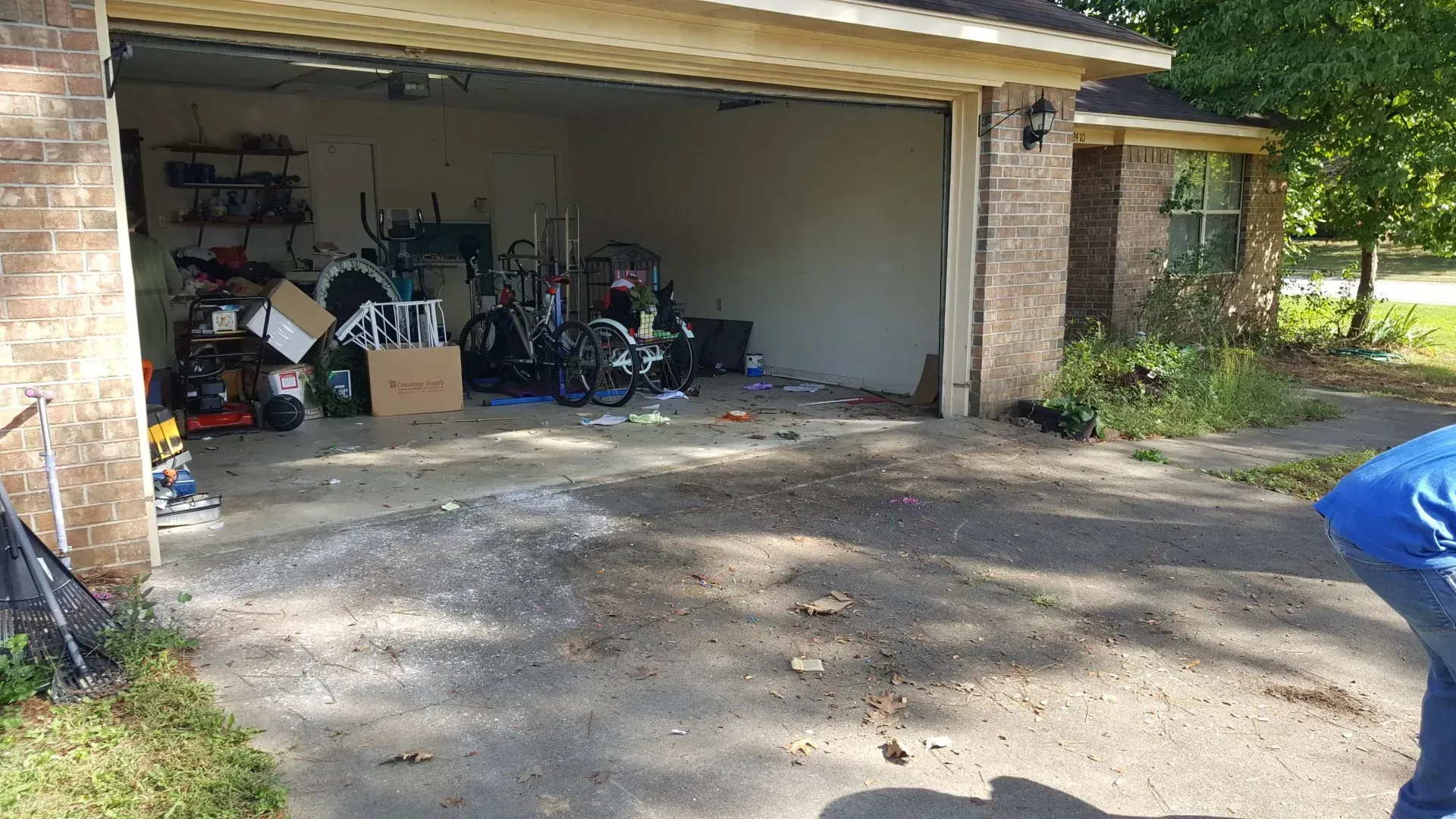 A person is standing in front of a garage filled with junk.