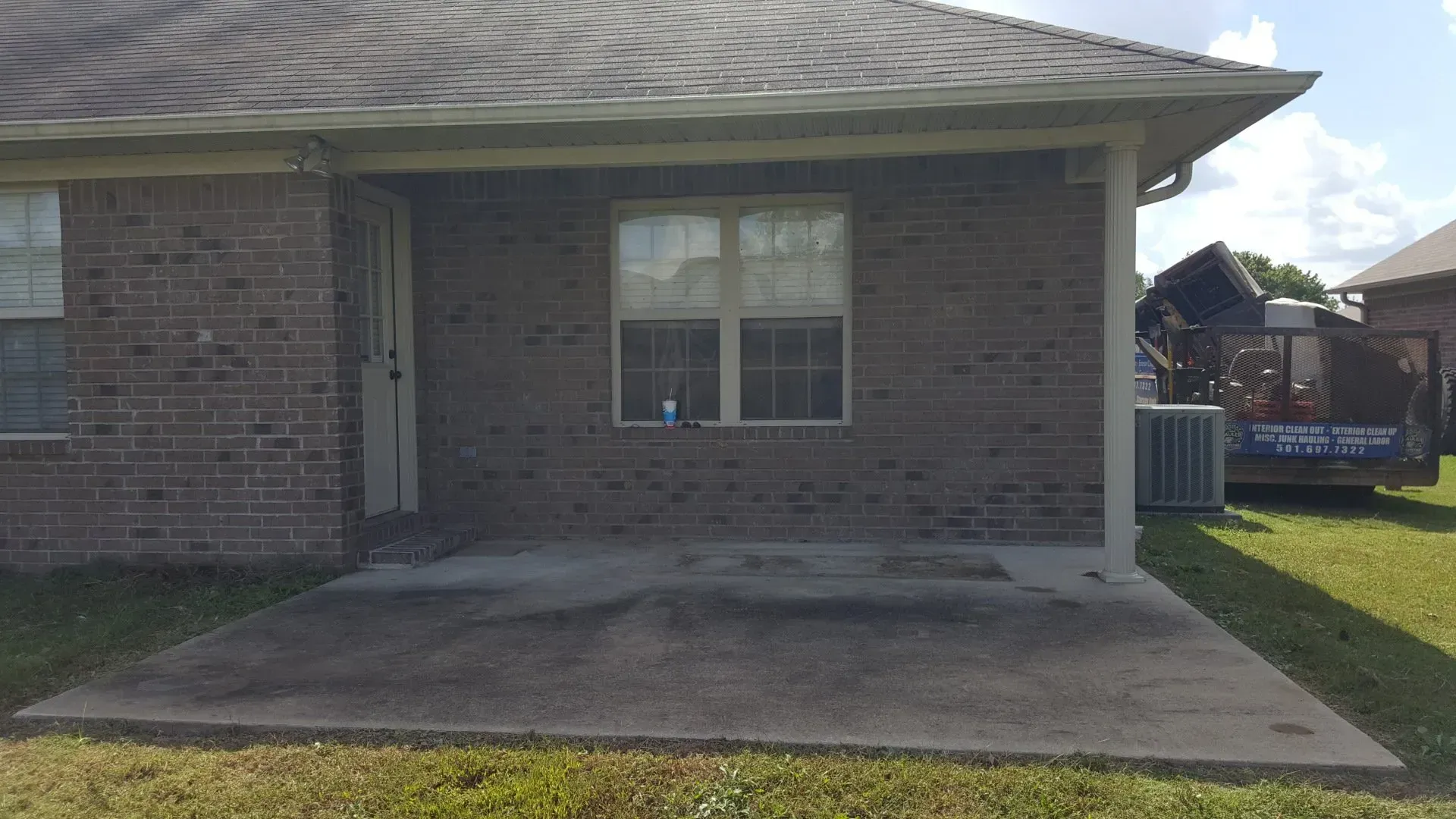 A brick house with a concrete patio in front of it.