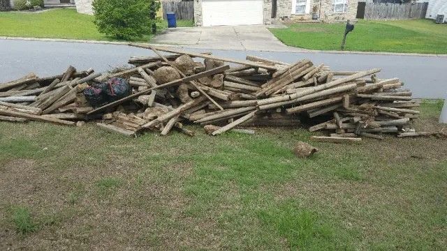 A pile of wood is sitting in the grass in front of a house.