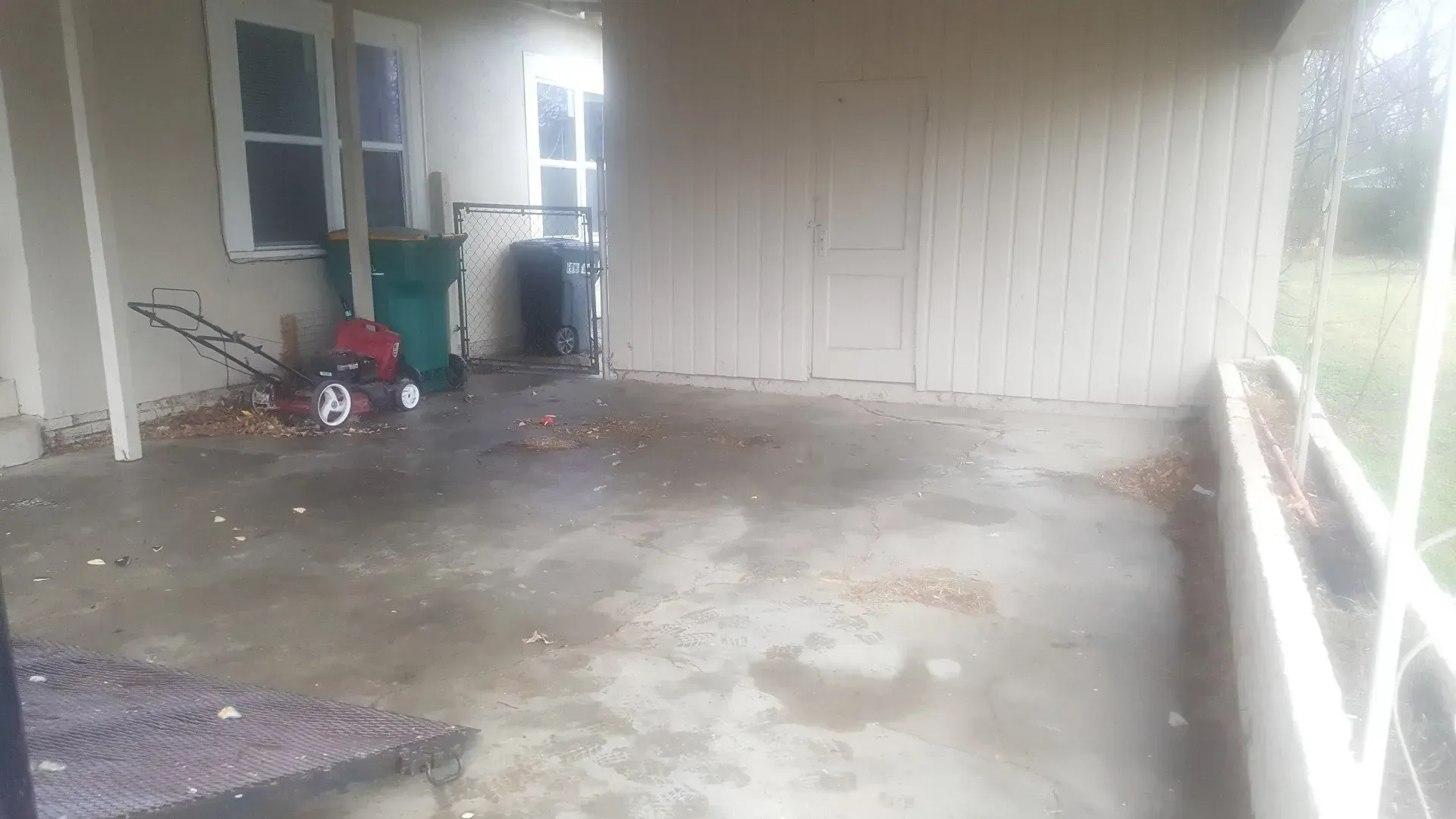 A dirty garage with a lawn mower and a trash can.
