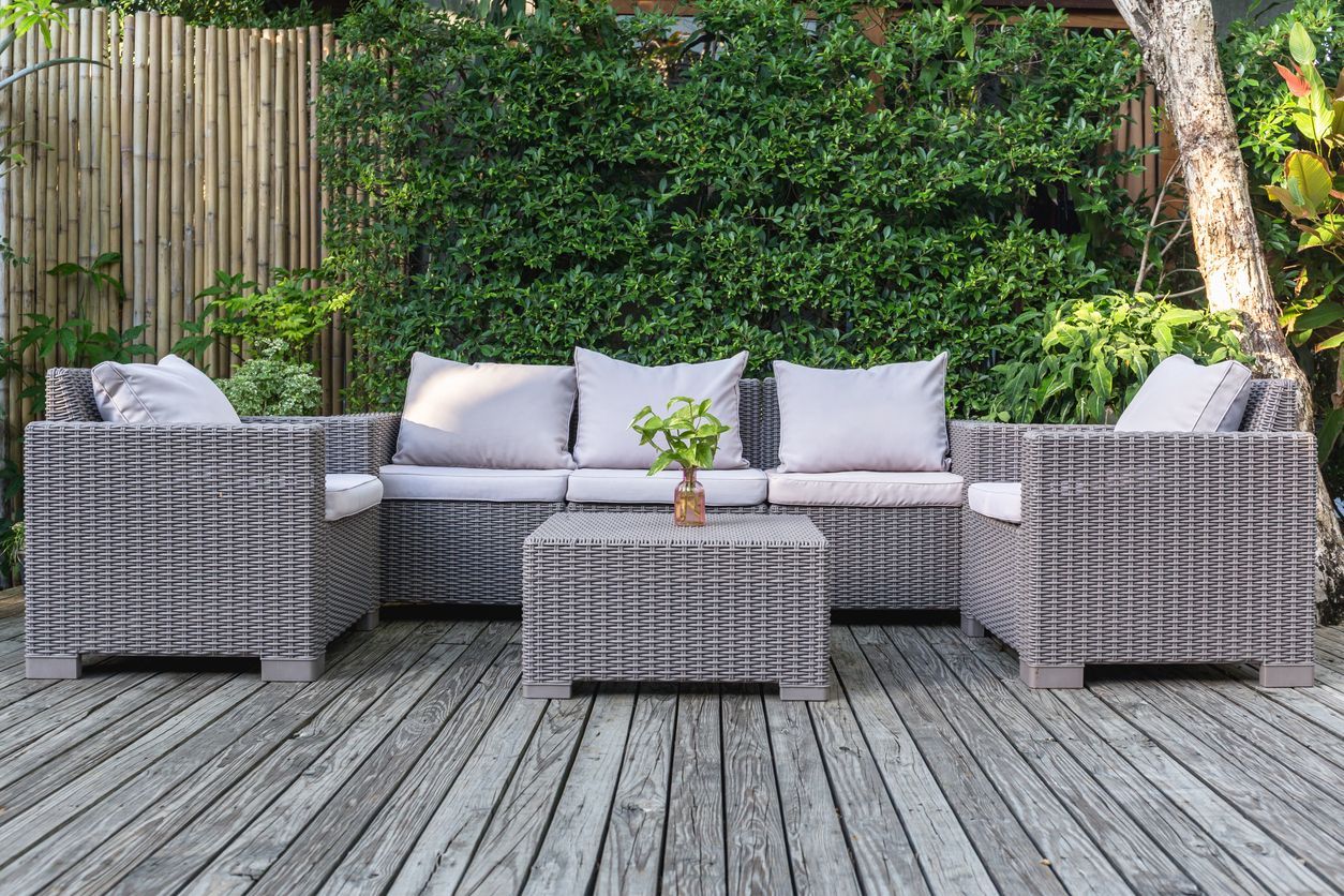 A wicker patio set is sitting on a wooden deck.
