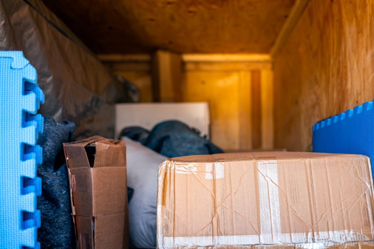 The inside of a moving truck filled with boxes and blankets.