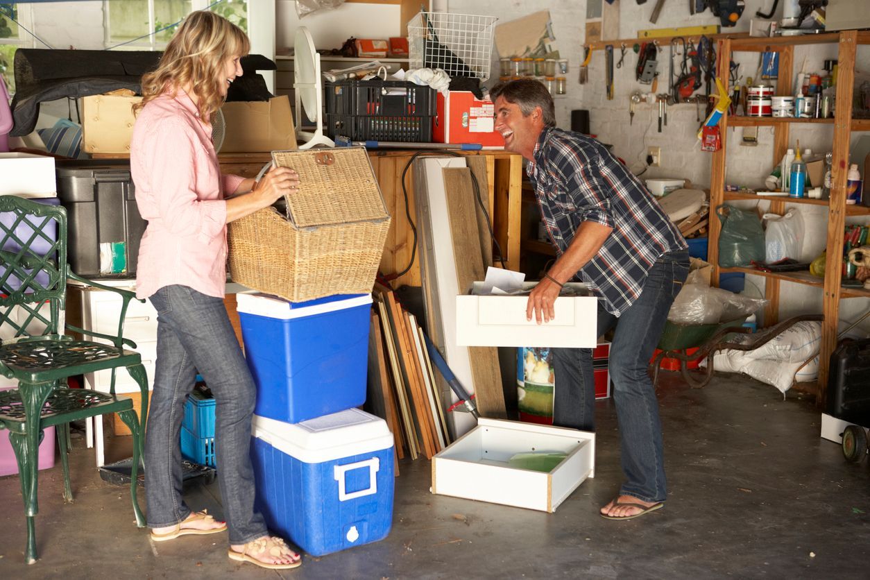 A man and a woman are moving boxes in a garage