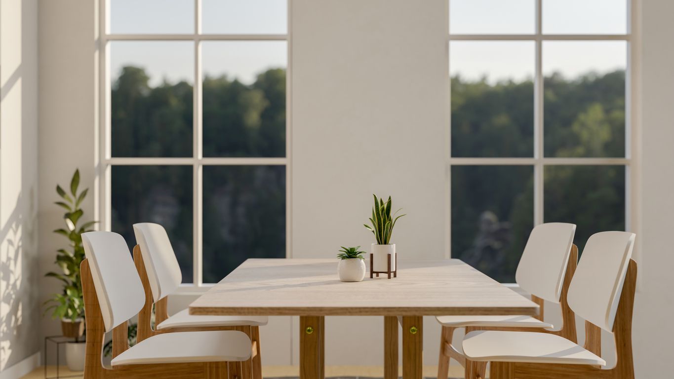 A dining room with a table and chairs in front of a large window.