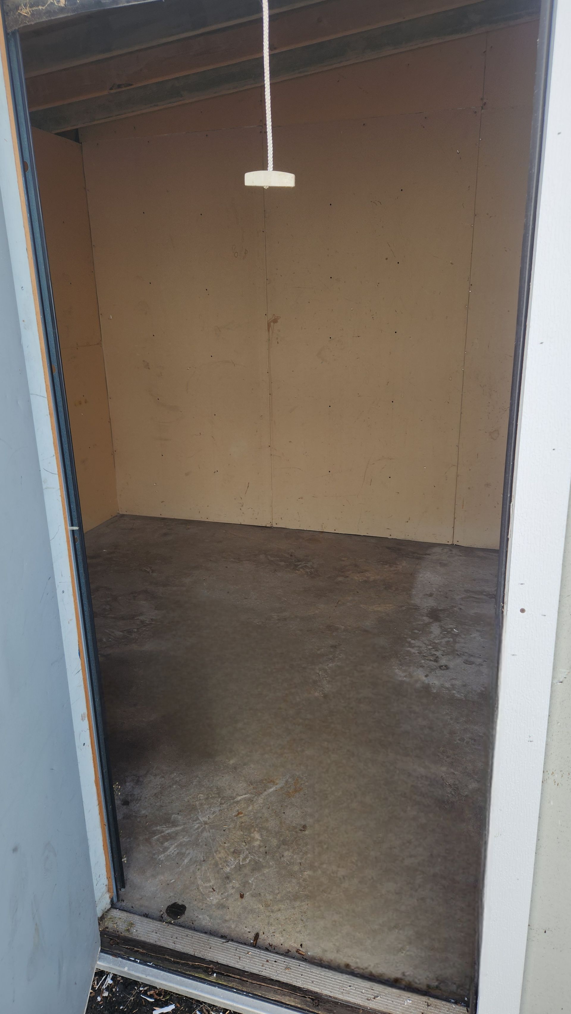 Empty storage unit with concrete floor and light tan walls.