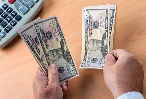 A person is holding two stacks of 20 dollar bills in their hands.