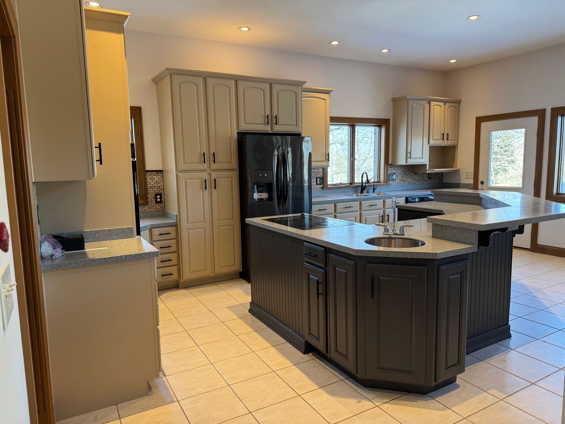 A large kitchen with a large island and a refrigerator.