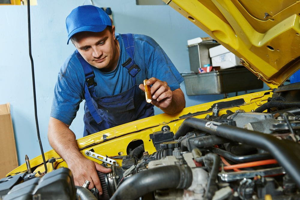 A Man Is Working On A Car Engine With The Hood Open — Ag Auto Spark in Nyngan, NSW