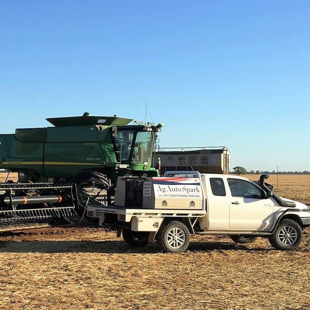 A White Truck Is Parked In A Field Next To A Combine Harvester — Ag Auto Spark in Narromine, NSW