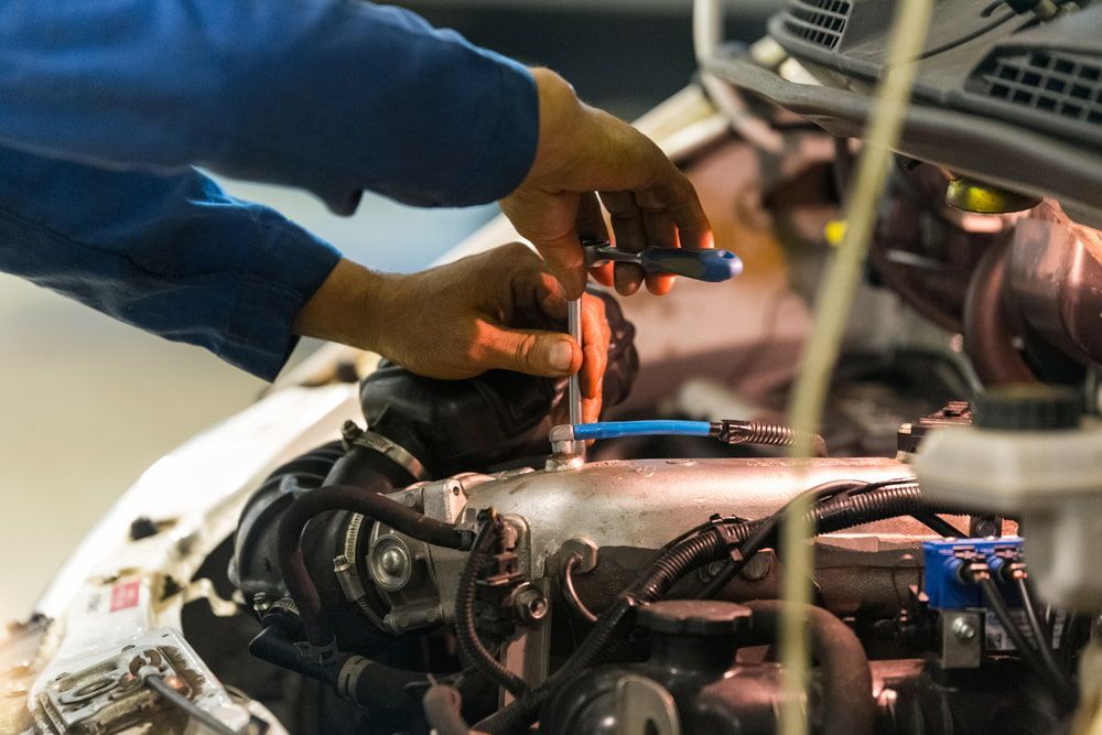 A Man Is Working On A Car Engine With A Wrench — Ag Auto Spark in Walgett, NSW
