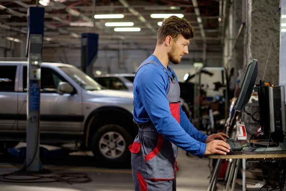 A Mechanic Is Working On A Computer In A Garage — Ag Auto Spark in Bourke, NSW