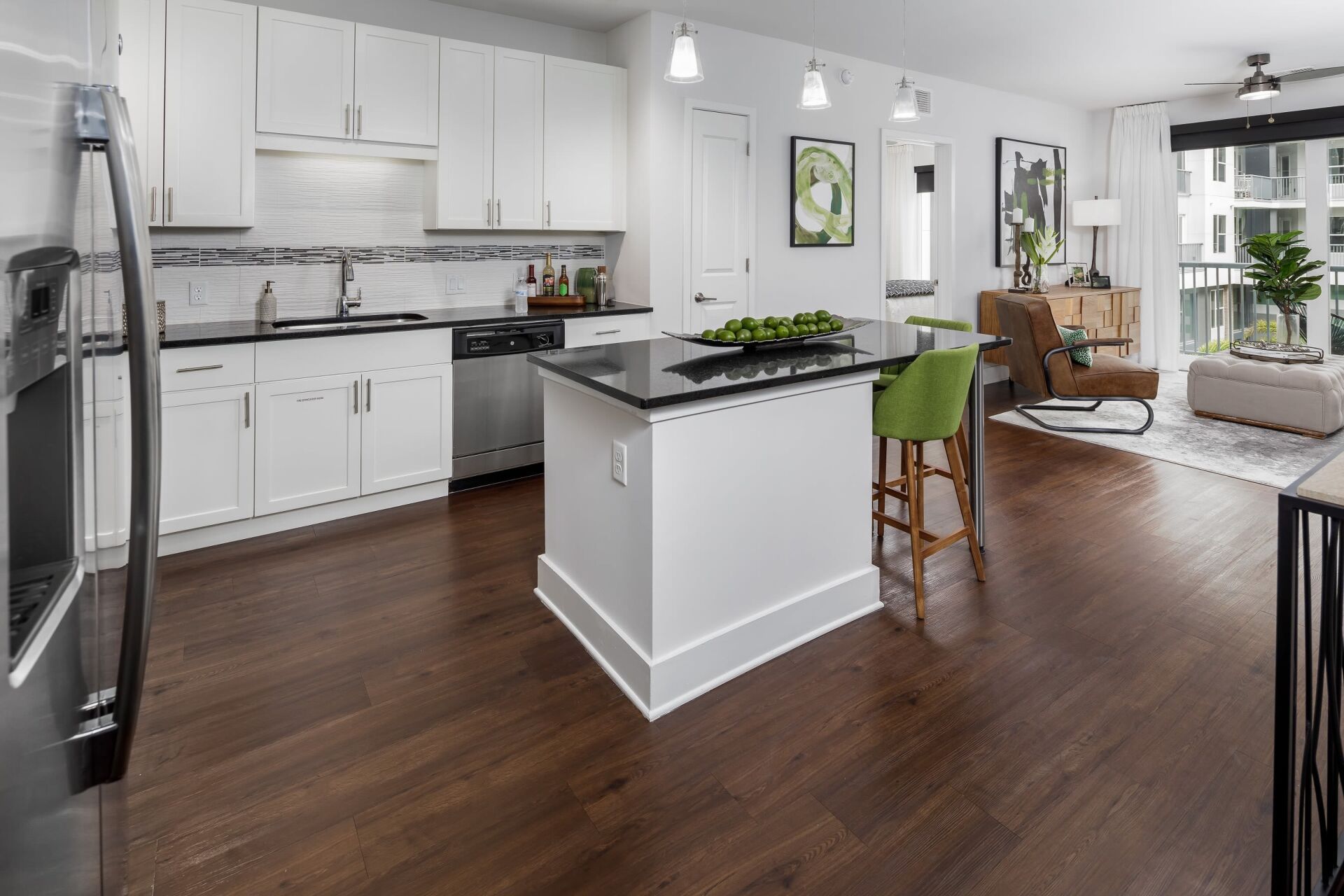 A kitchen with white cabinets and stainless steel appliances and a large island in the middle of the room.