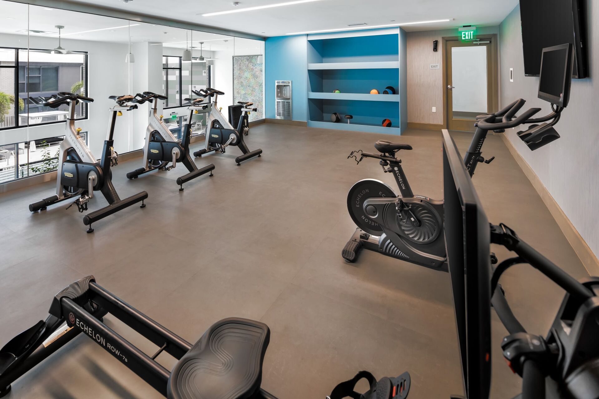 A gym with a lot of exercise equipment and a television on the wall.