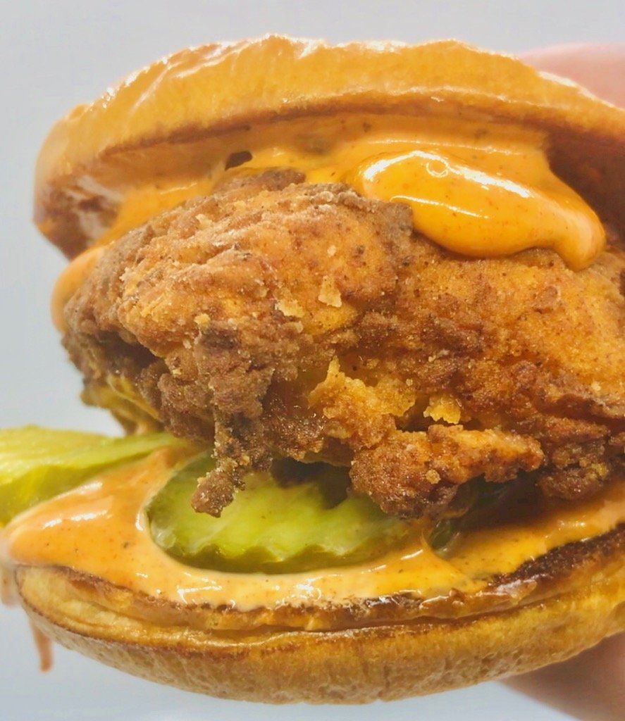 fried chicken sandwich on a bun with pickles and sauce