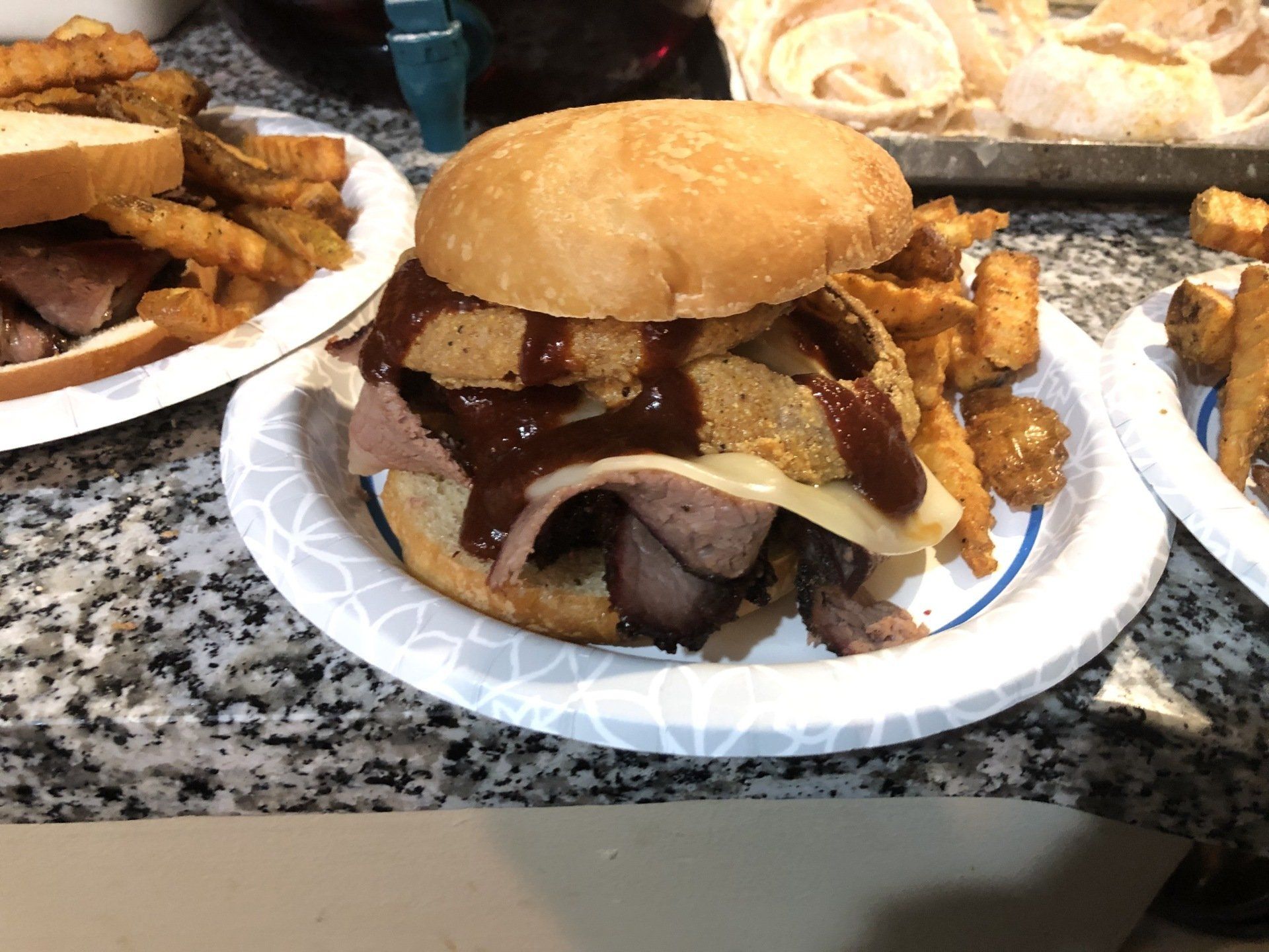 Z-man sandwich with brisket and sauce on a white paper plate