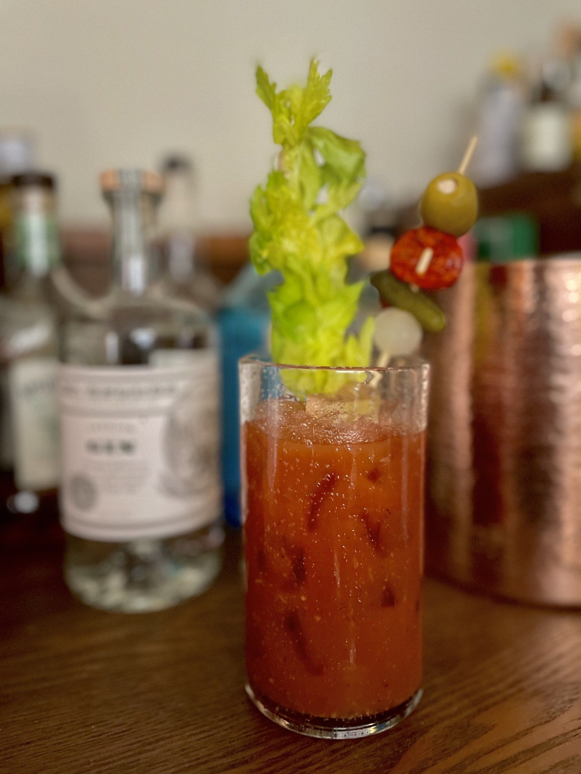 red bloody mary cocktail with a garnish of pickles, olives and celery