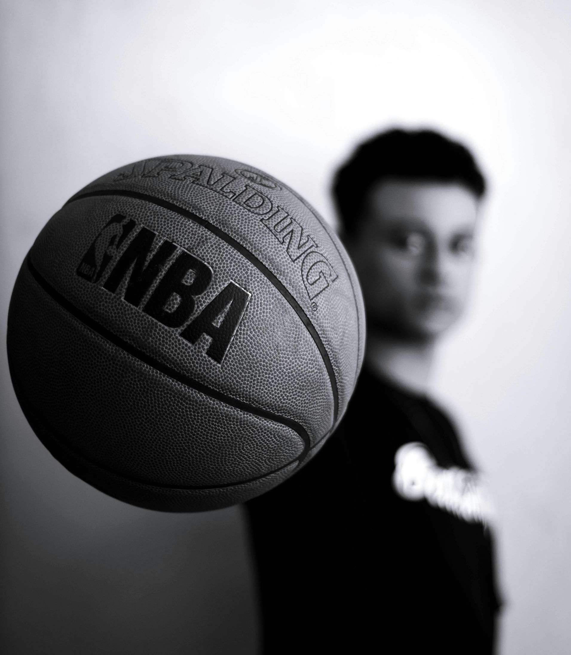A black and white photo of a basketball player holding a ball out close to the camera with his right hand