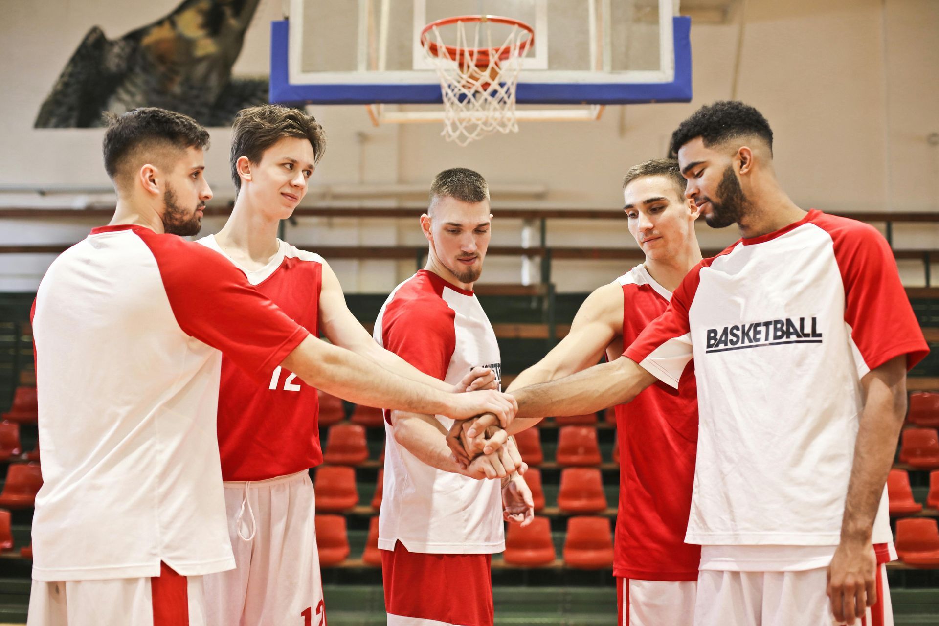 A group of basketball players are putting their hands together on a court.
