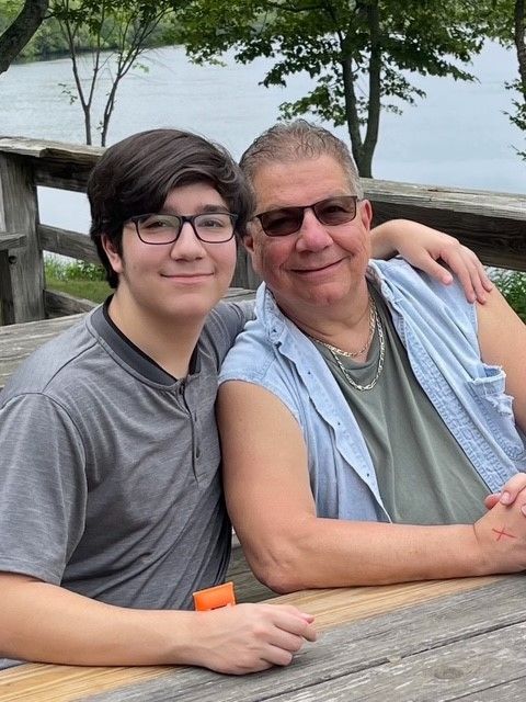 A green canoe and a red kayak are on the shore of a lake.