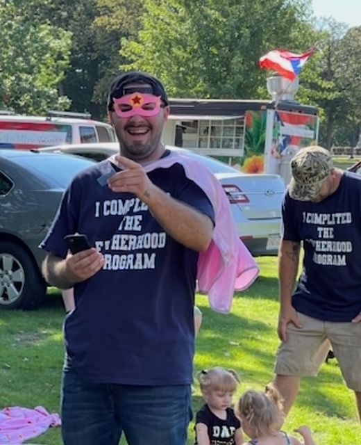 A woman in a pink shirt is holding a football in her hand.