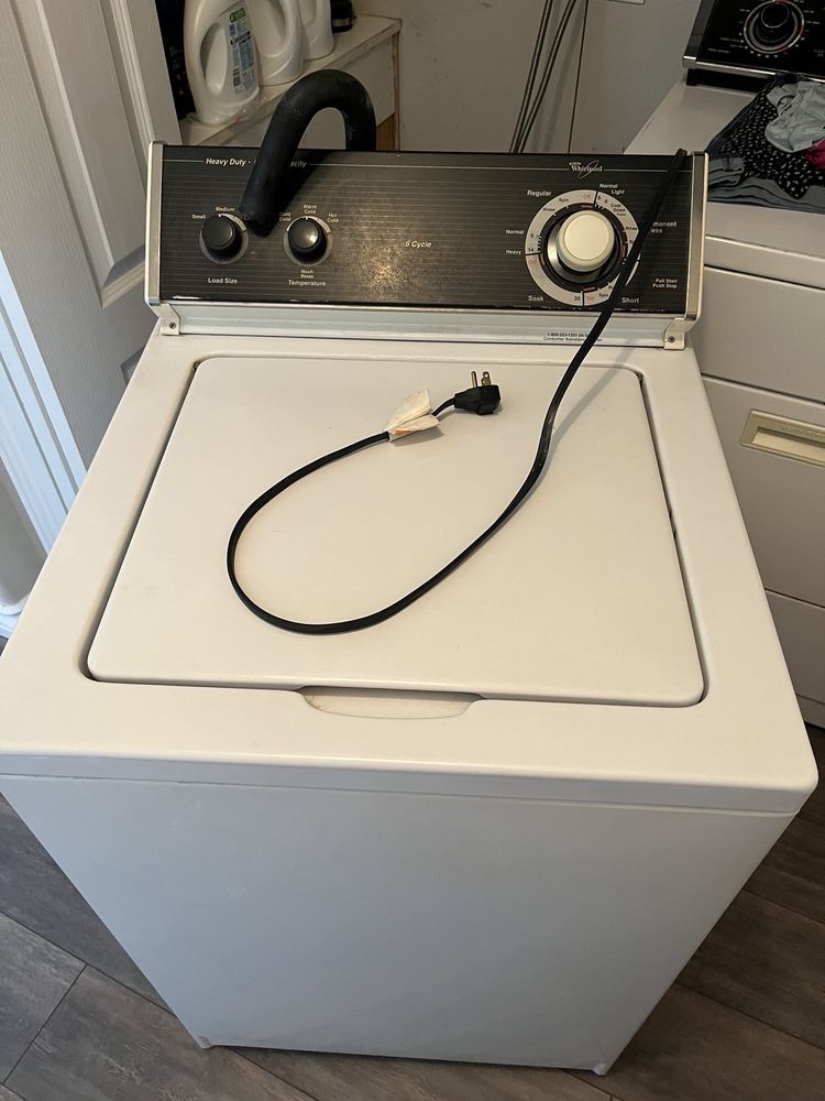 A white washing machine with a black cord attached to it.