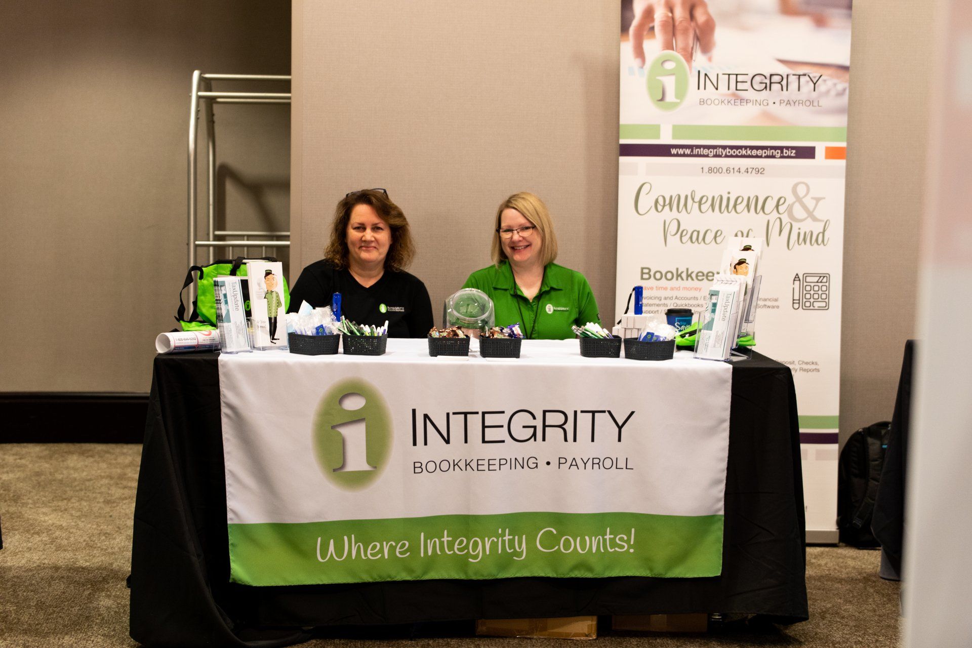 Two women are sitting at a table with a banner that says integrity.