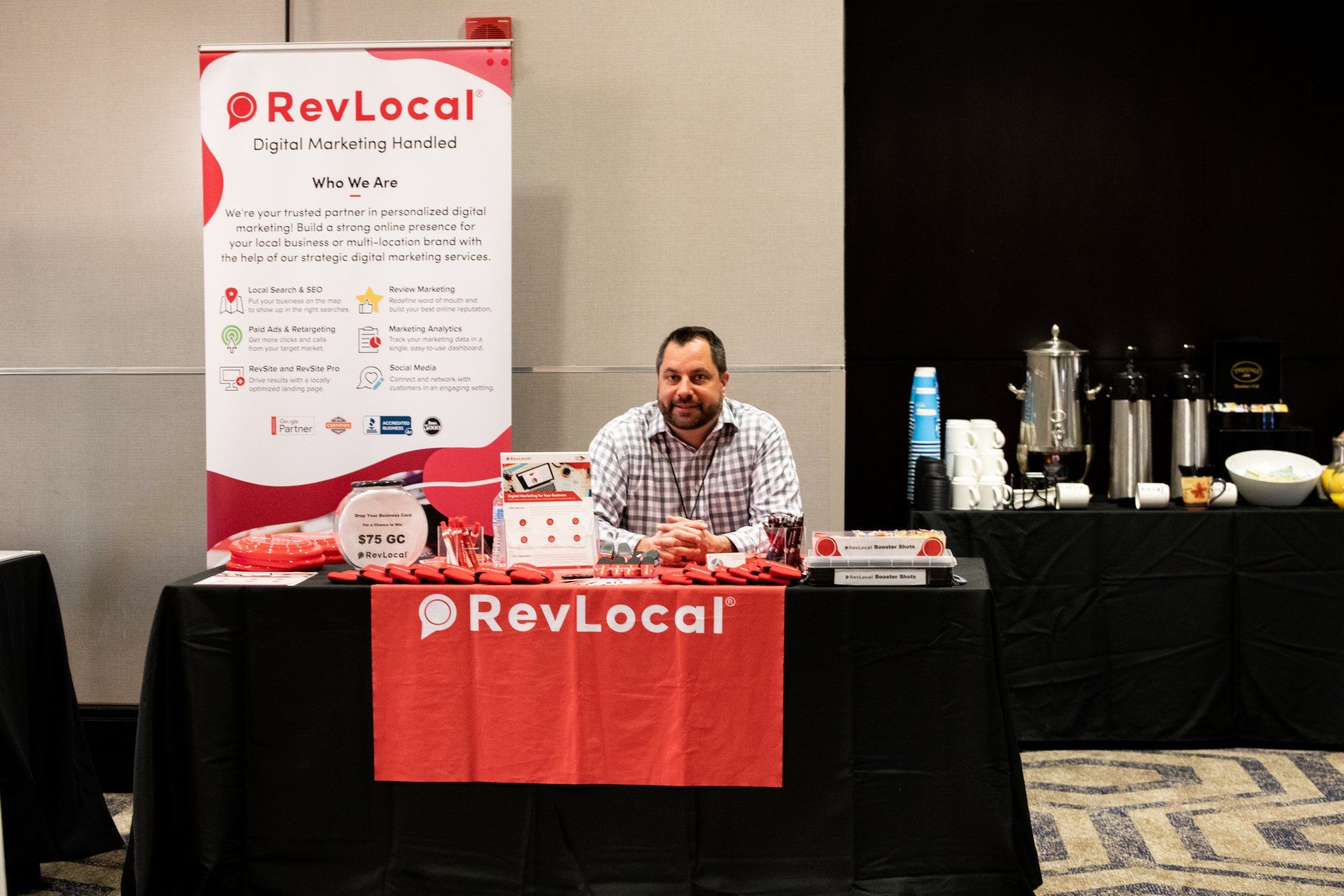 A man is sitting at a table with a sign that says revlocal on it.