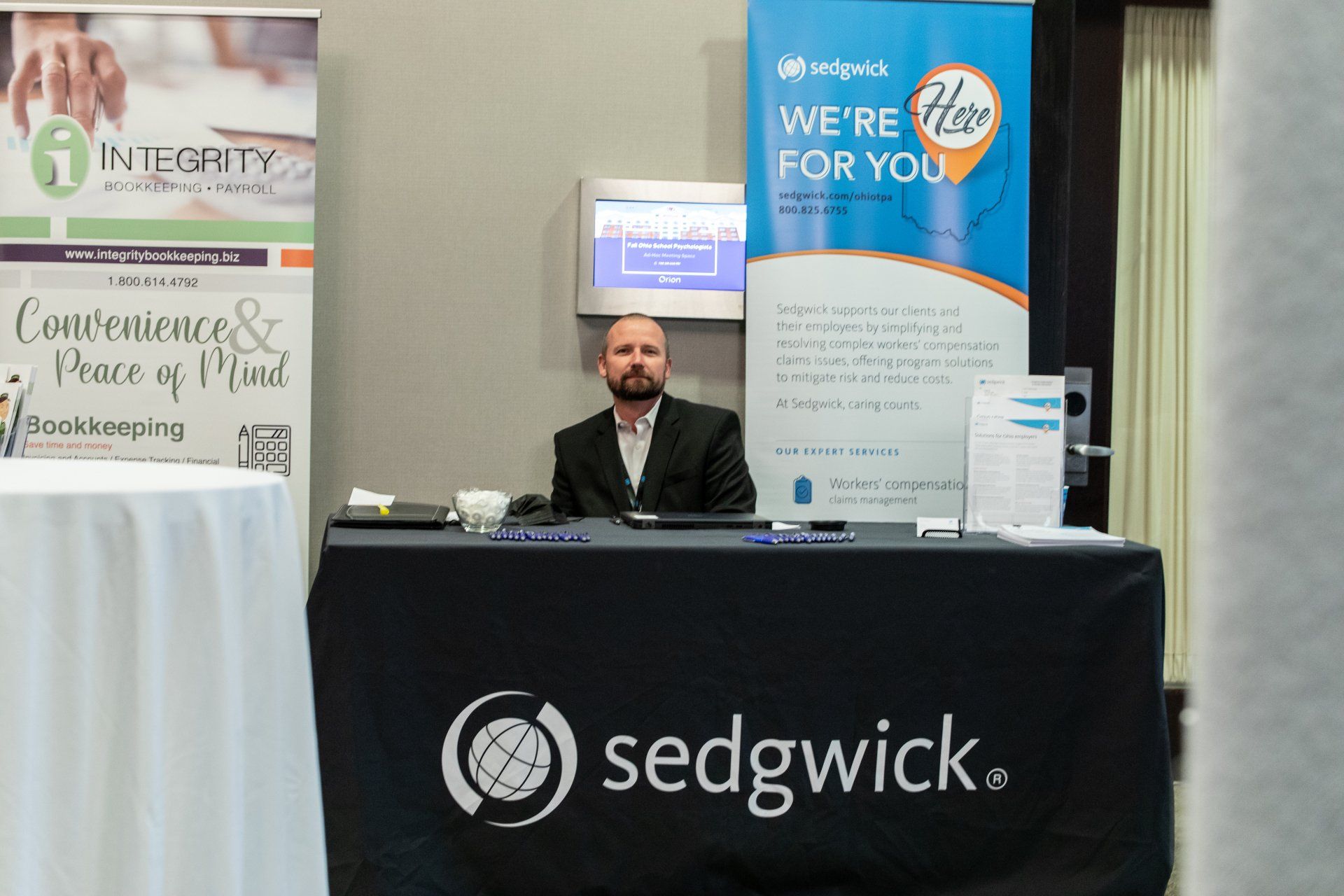 A man stands behind a desk that says sedgwick on it